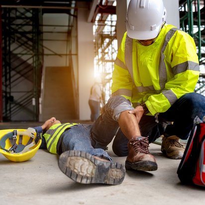 Bouwmedewerker verleent eerste hulp aan gewonde collega op bouwplaats na arbeidsongeval.