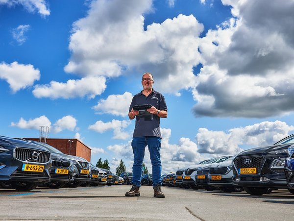 Inspecteur voert een voertuiginspectie uit op een parkeerterrein met auto’s.