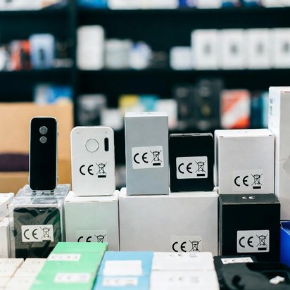 Elektronische apparaten en verpakkingen met zichtbare CE-markering, uitgestald op dozen in een winkelomgeving.