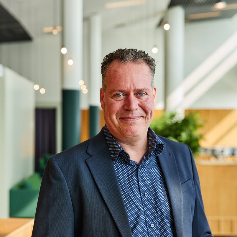 TÜV NORD medewerker glimlacht in kantooromgeving.