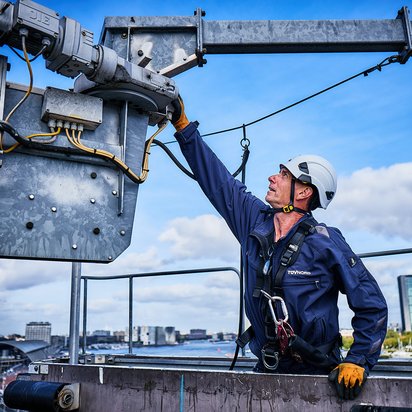 Lees het nieuwsartikel over wanneer een nieuwe keuring nodig is. TÜV NORD inspecteur op een gevelonderhoudsinstallatie