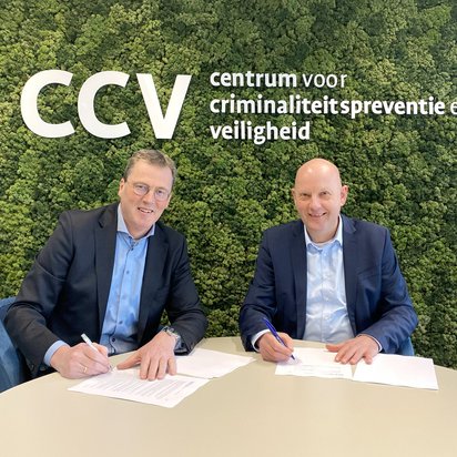 Het ondertekenen van de samenwerkingsovereenkomst aan tafel, met op de achtergrond het logo van CCV (Centrum voor Criminaliteitspreventie en Veiligheid).